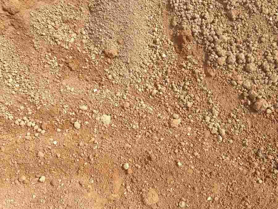 Close-up of dry, reddish-brown dirt and small pebbles with a rough, uneven texture