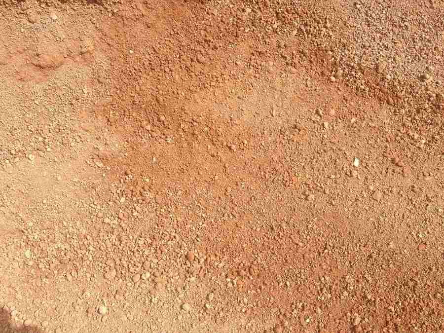 Close-up of rough orange-brown dirt or sand surface with small pebbles