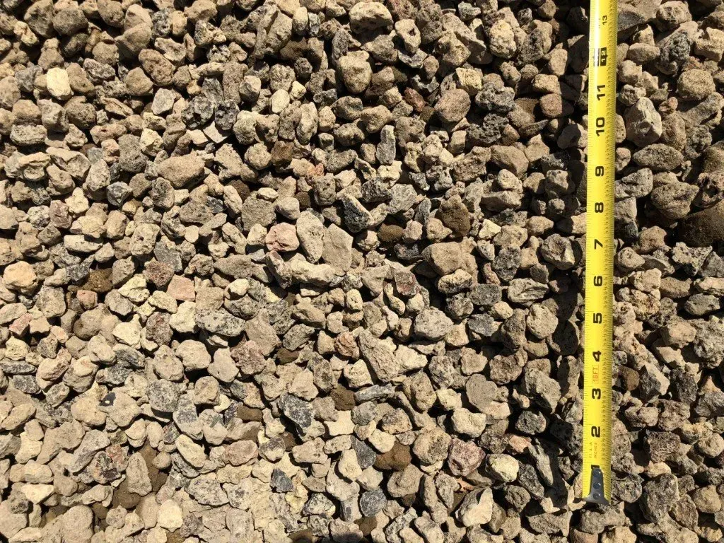 Pile of small brown gravel with a yellow measuring tape along the right side