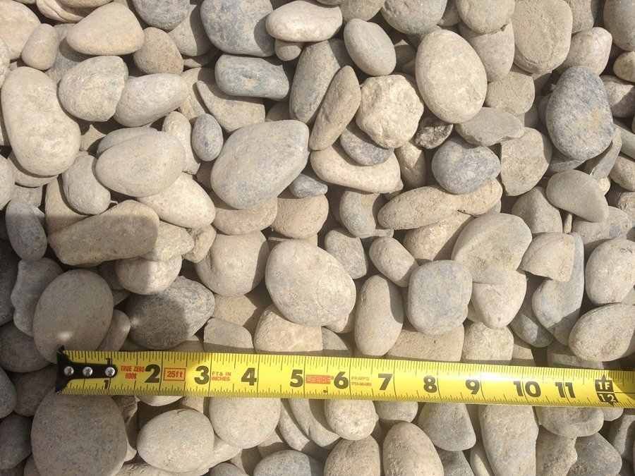 Small beige pebbles with a yellow tape measure along the bottom edge.