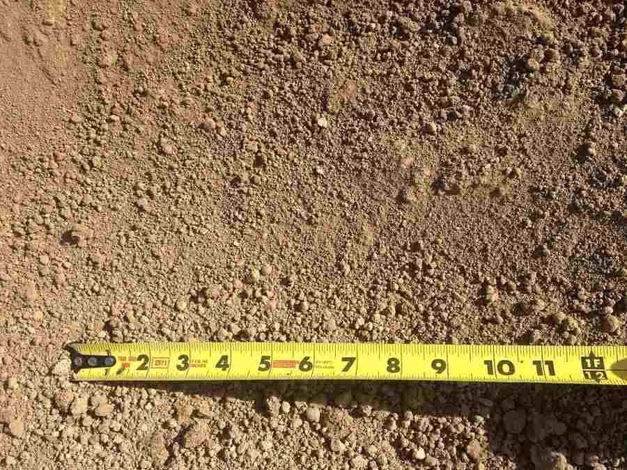 Close-up of brown soil with a yellow measuring tape laid across the bottom edge.