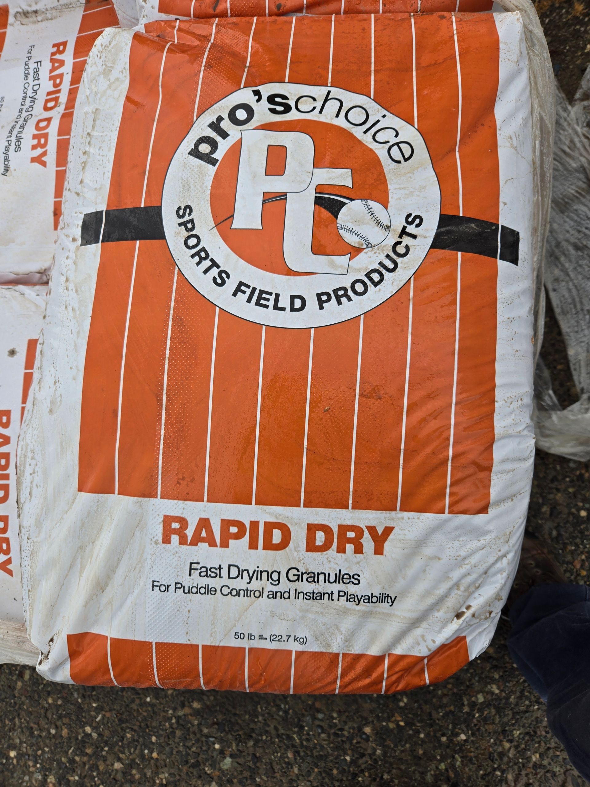 Orange-and-white bag of Pro’s Choice Rapid Dry sports field products on a gravel surface