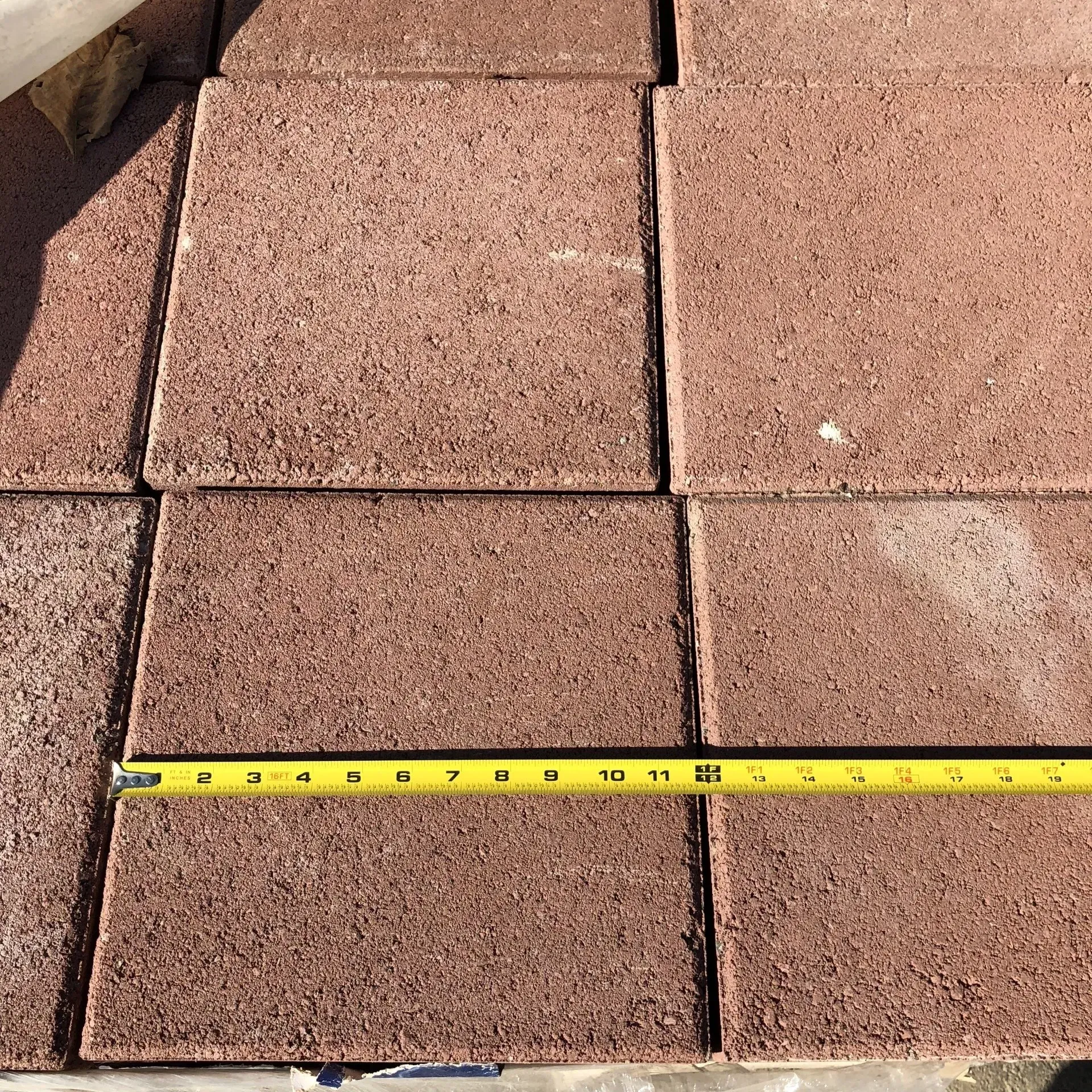 Tape measure stretched across reddish-brown roof tiles under bright sunlight