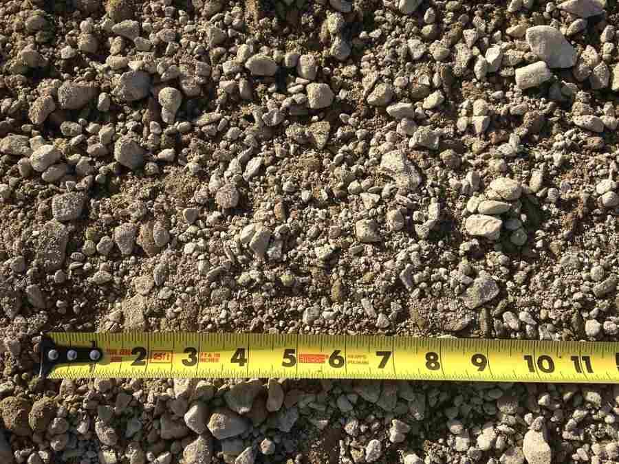 Close-up of gravel with a yellow measuring tape laid across the bottom edge