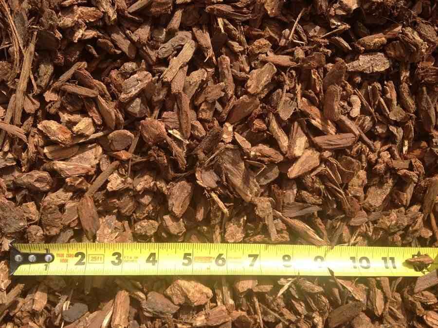 Brown wood chips with a yellow measuring tape laid across the bottom edge.