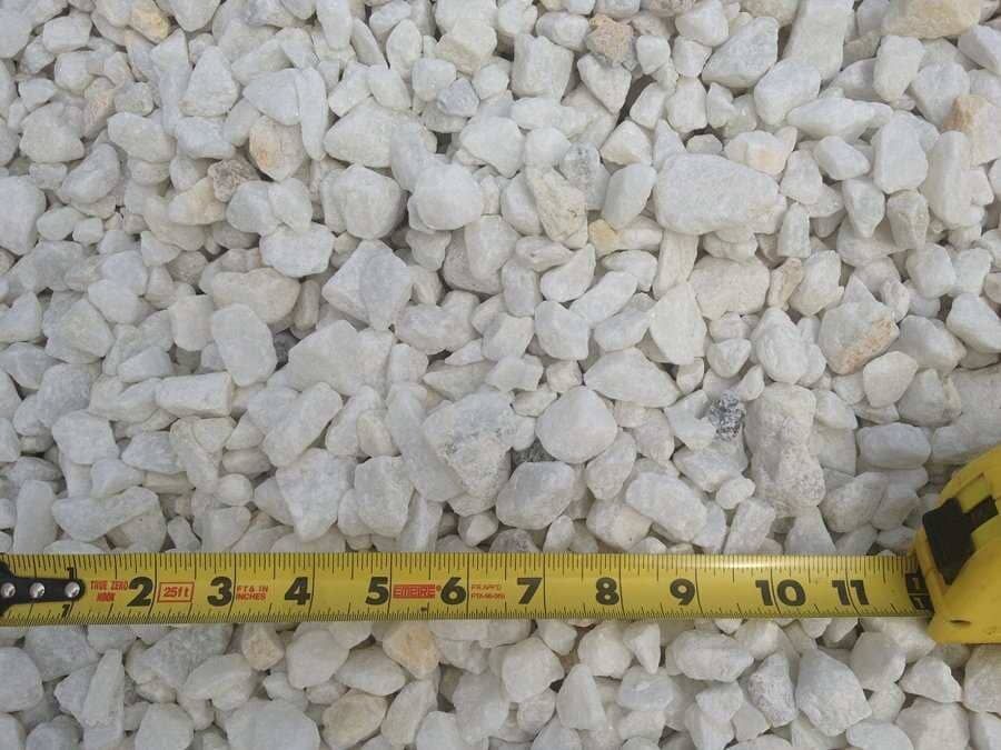 Yellow measuring tape laid across white gravel stones.