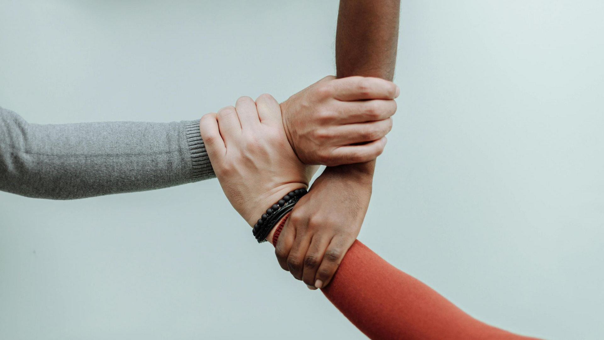 Three arms linked together, wrists clasped, forming a triangle.