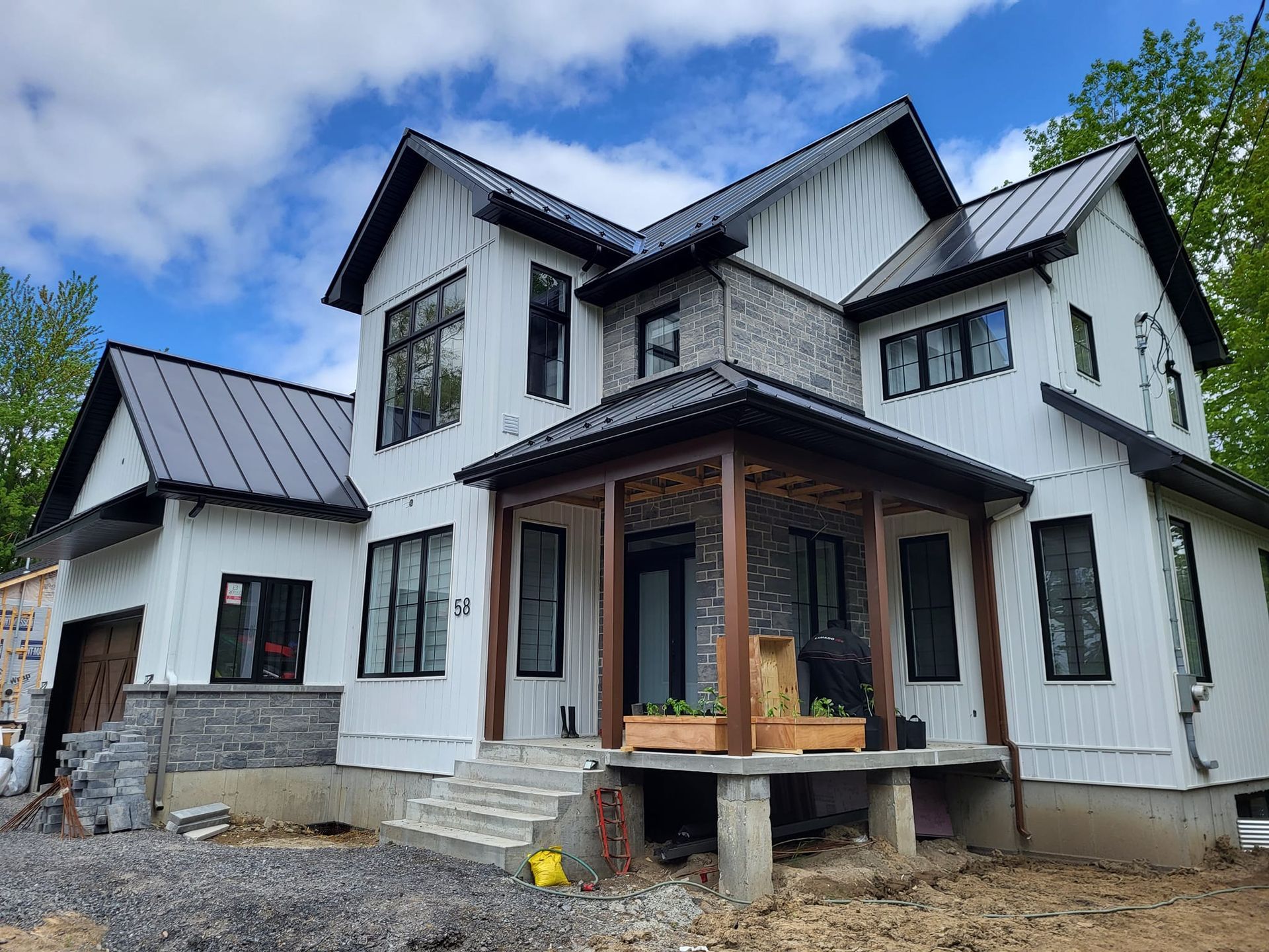 Une grande maison blanche avec un toit noir est en construction.