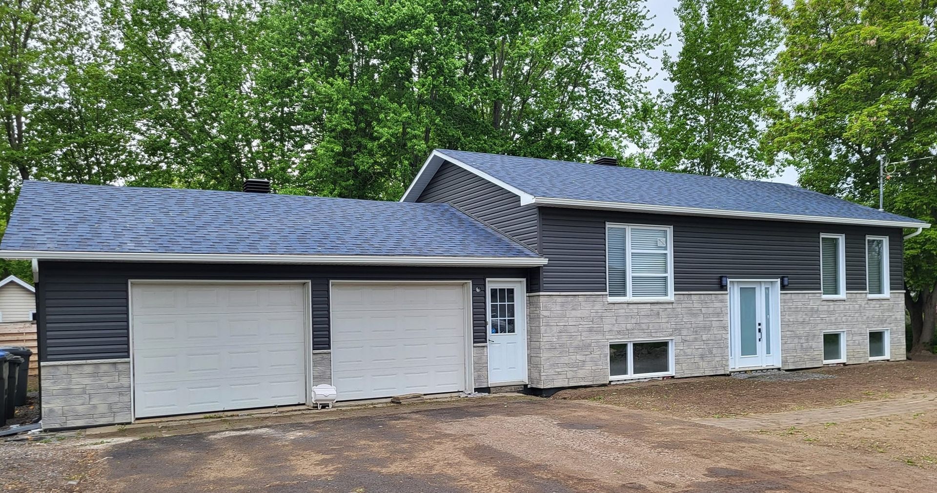 Une grande maison avec un toit bleu et deux portes de garage.