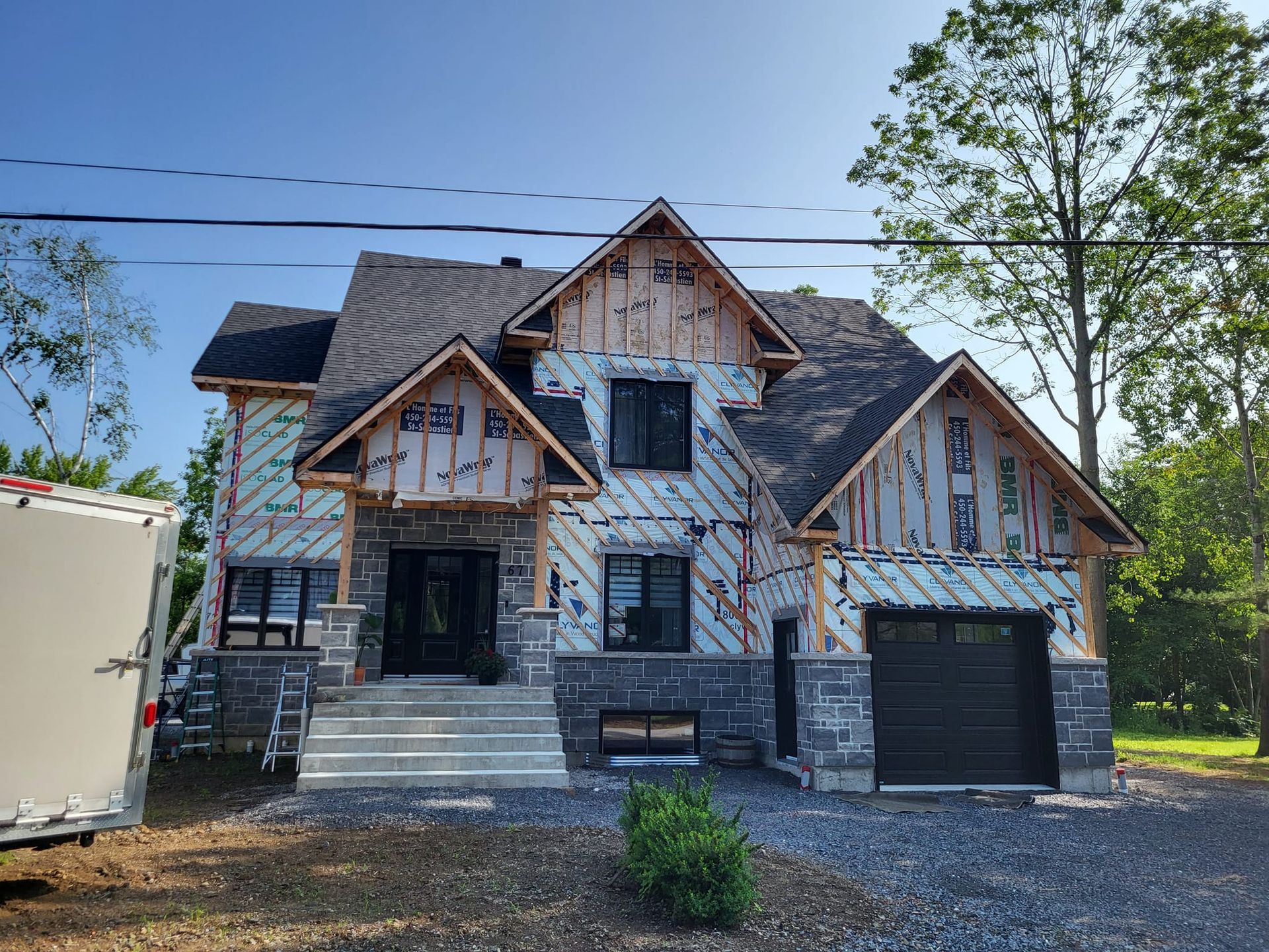 Une grande maison en construction avec une remorque garée devant.