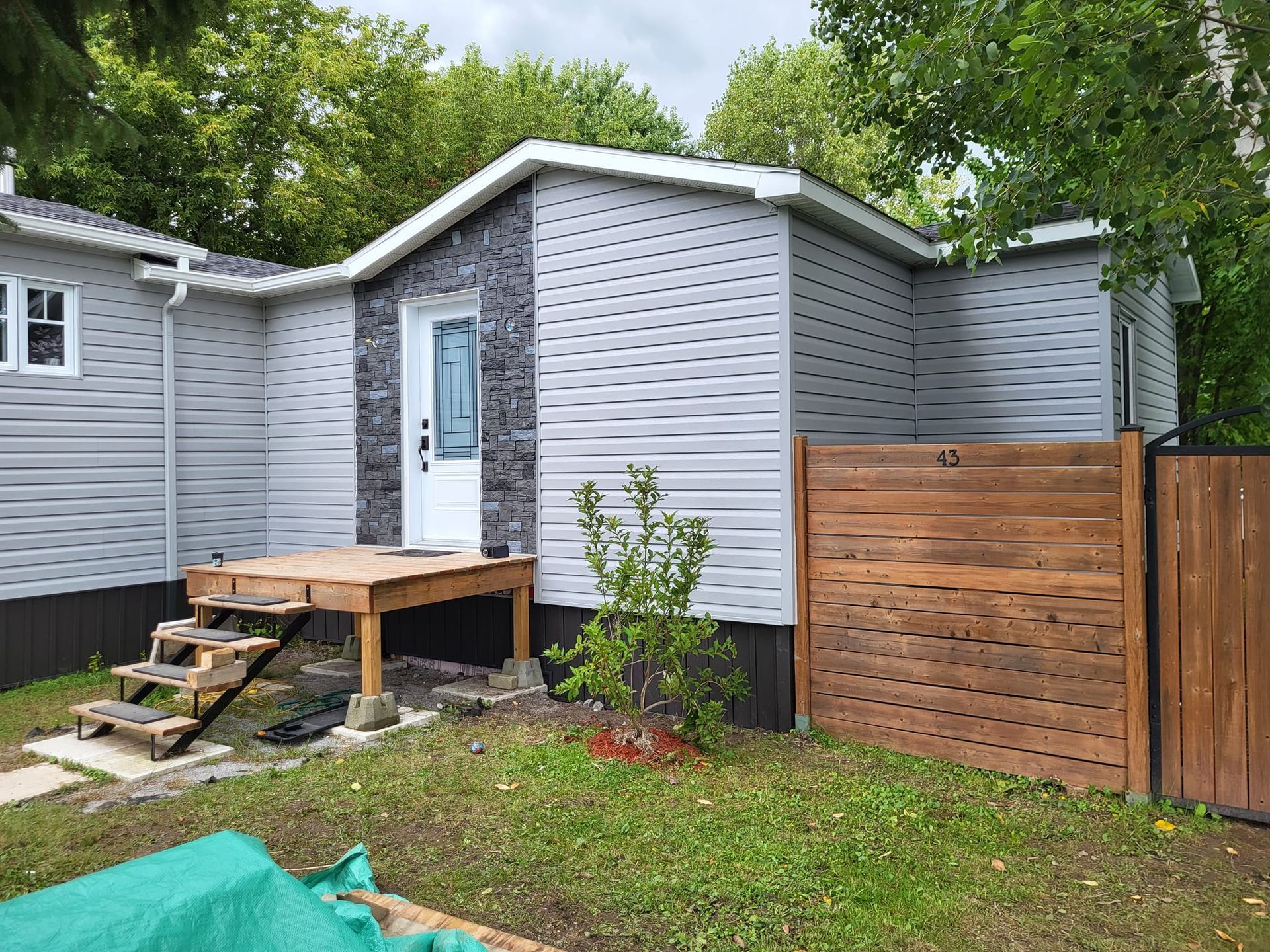 Une petite maison avec une clôture en bois et des escaliers devant.