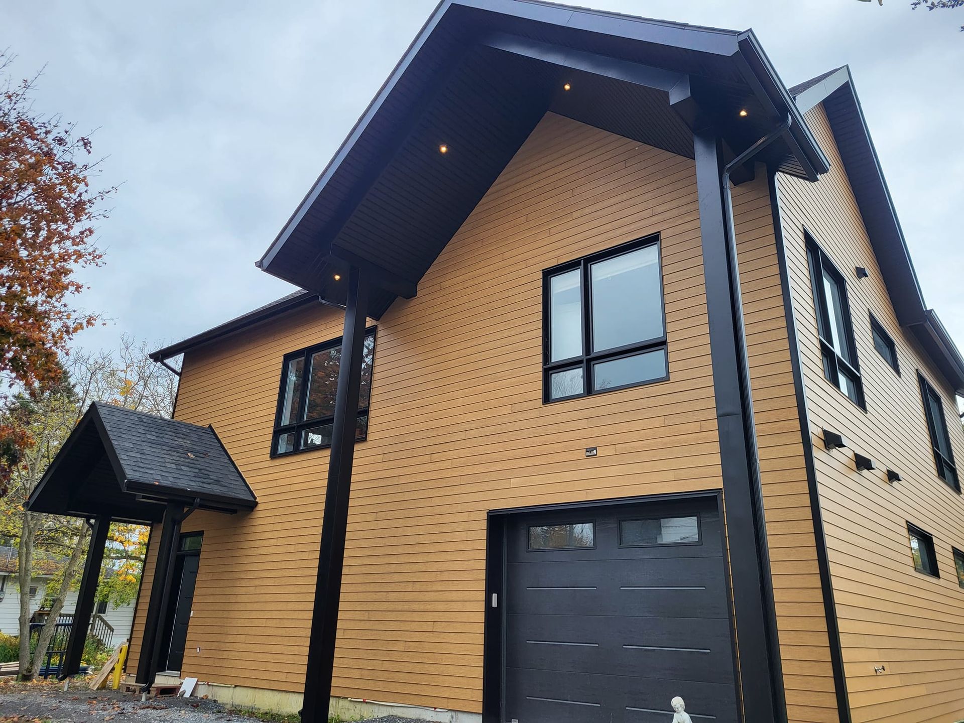 Une grande maison avec une porte de garage noire et un toit noir.