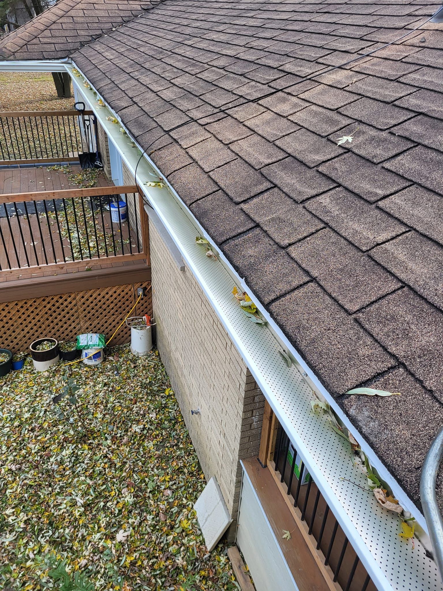 Une gouttière sur le côté d'une maison avec des feuilles dessus.
