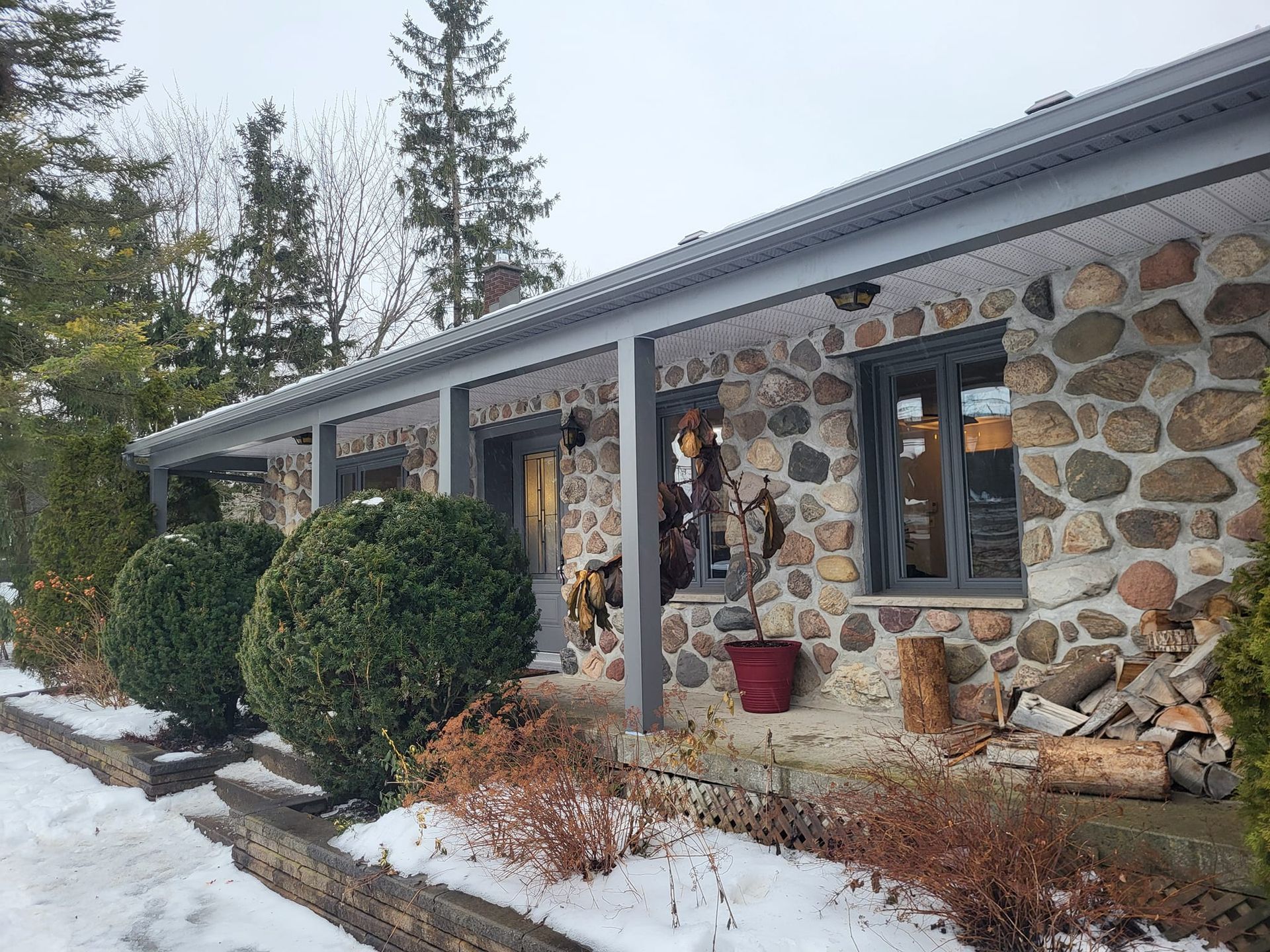 Une maison en pierre avec un porche sous la neige