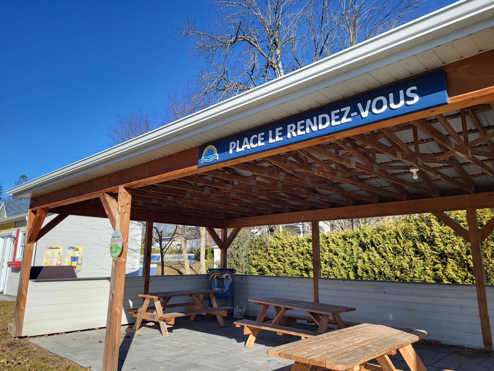 Un espace couvert avec des tables de pique-nique et un panneau indiquant place le rendez-vous