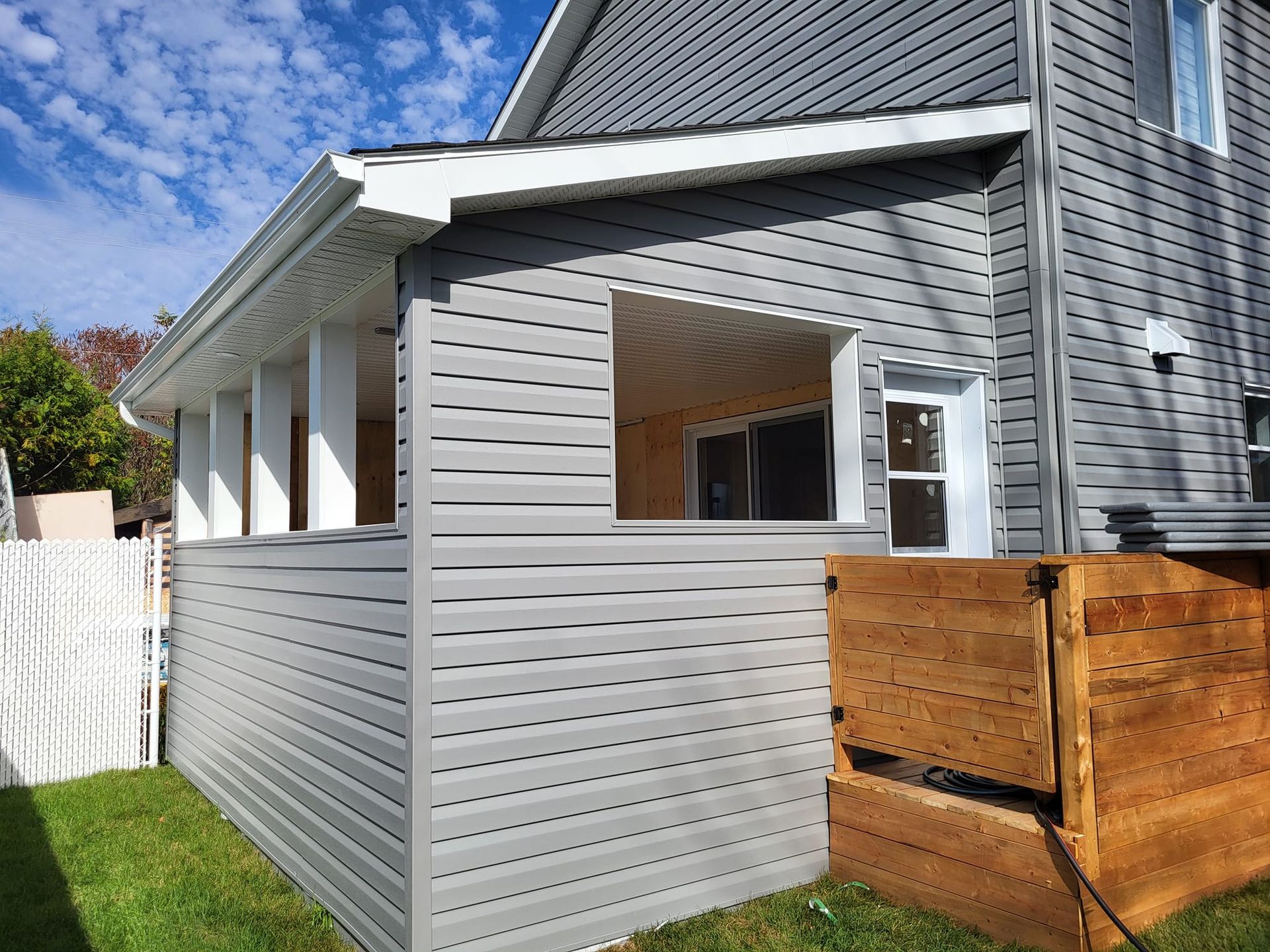 Le côté d'une maison avec un porche et une terrasse en bois
