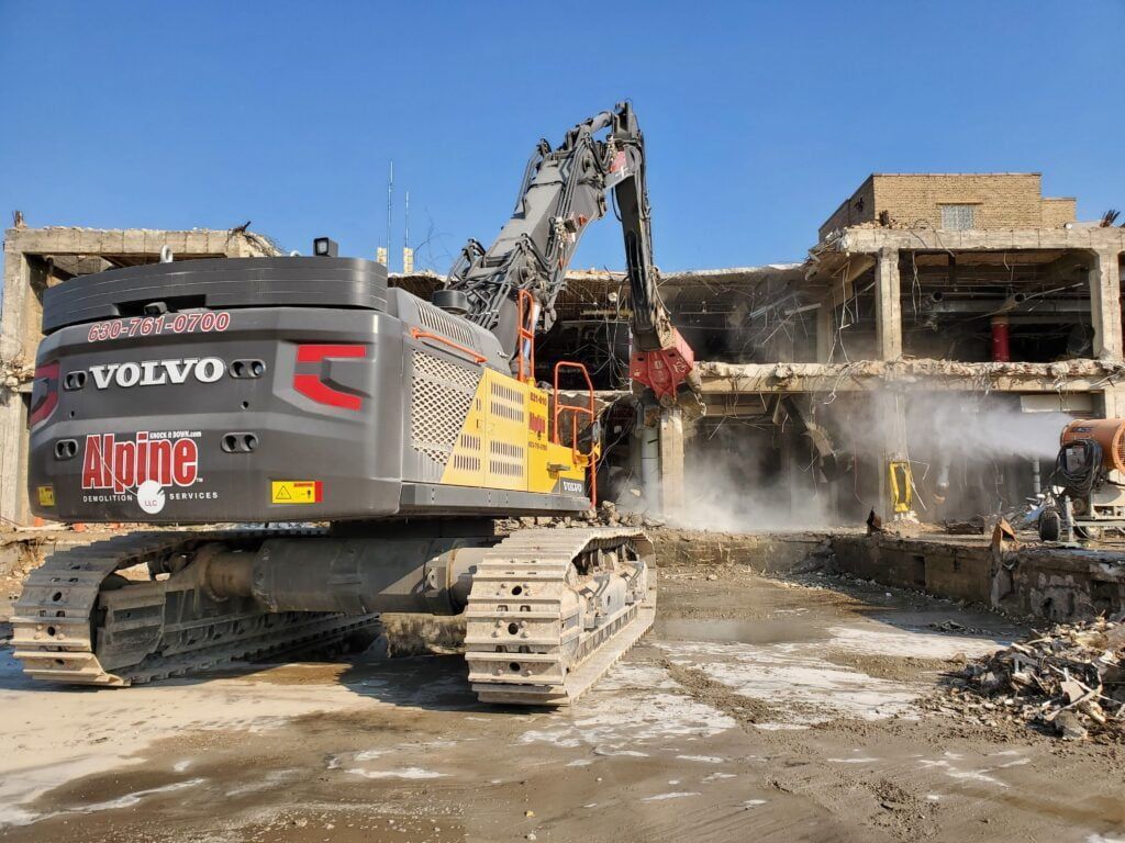 A volvo excavator is being used to demolish a building.