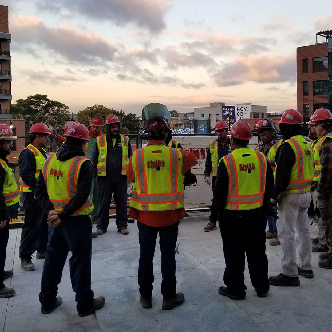 A group of construction workers wearing safety vests and hard hats