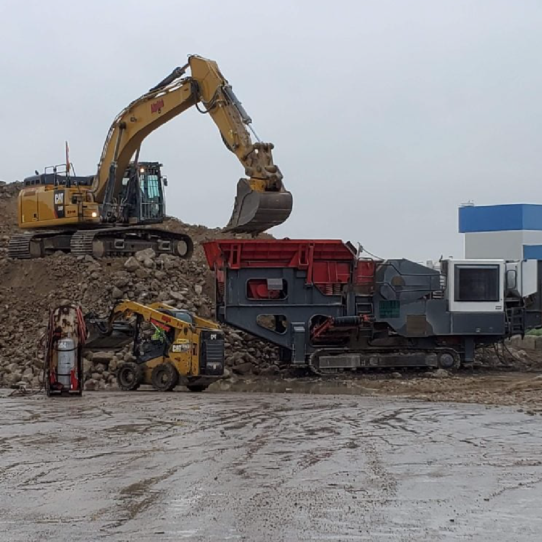 A yellow excavator is digging into a pile of dirt.