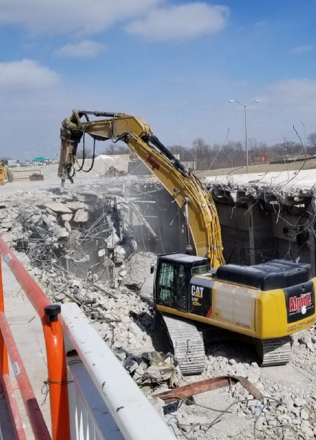 A large yellow excavator is demolishing a building.