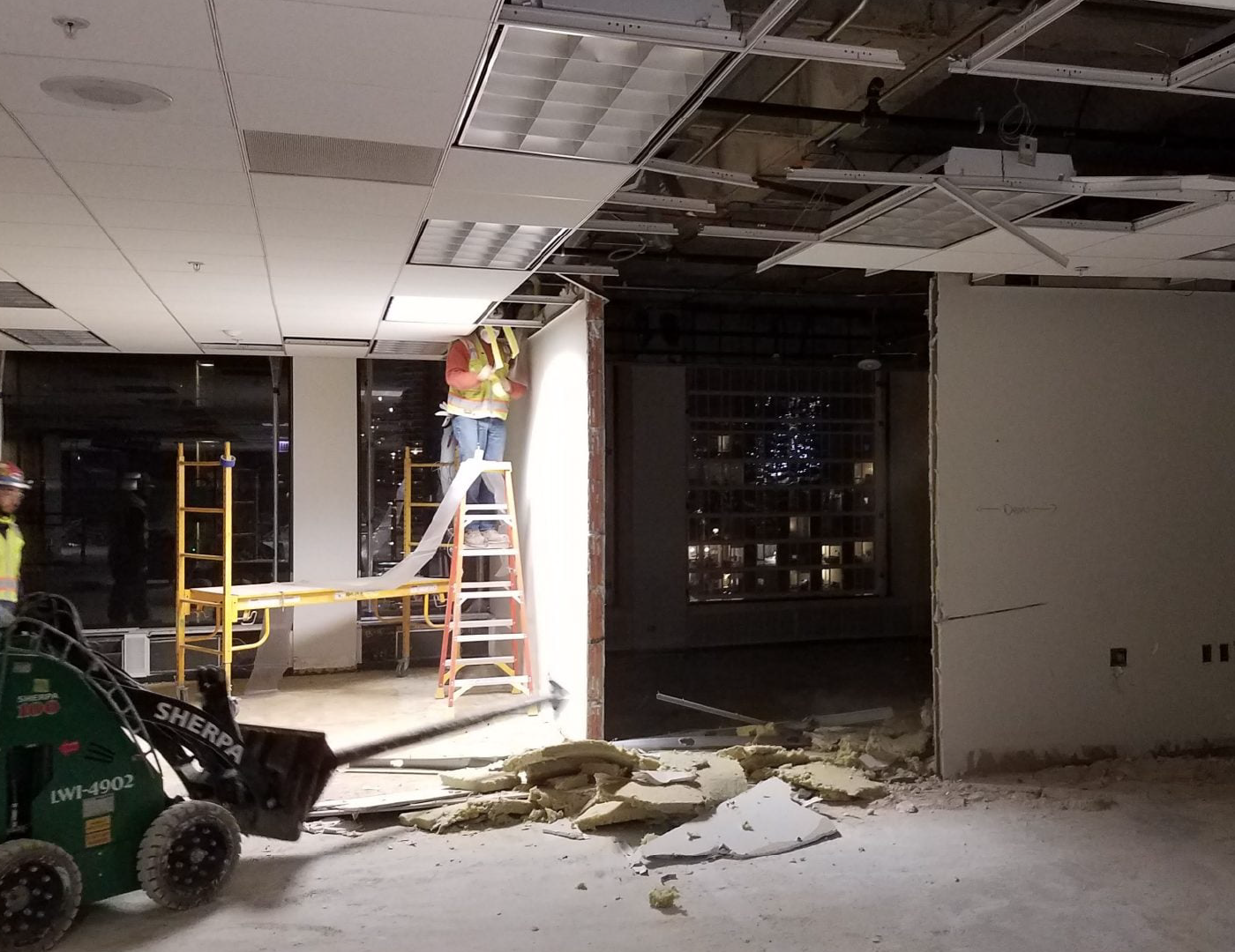 A man is standing on a ladder in a building under construction