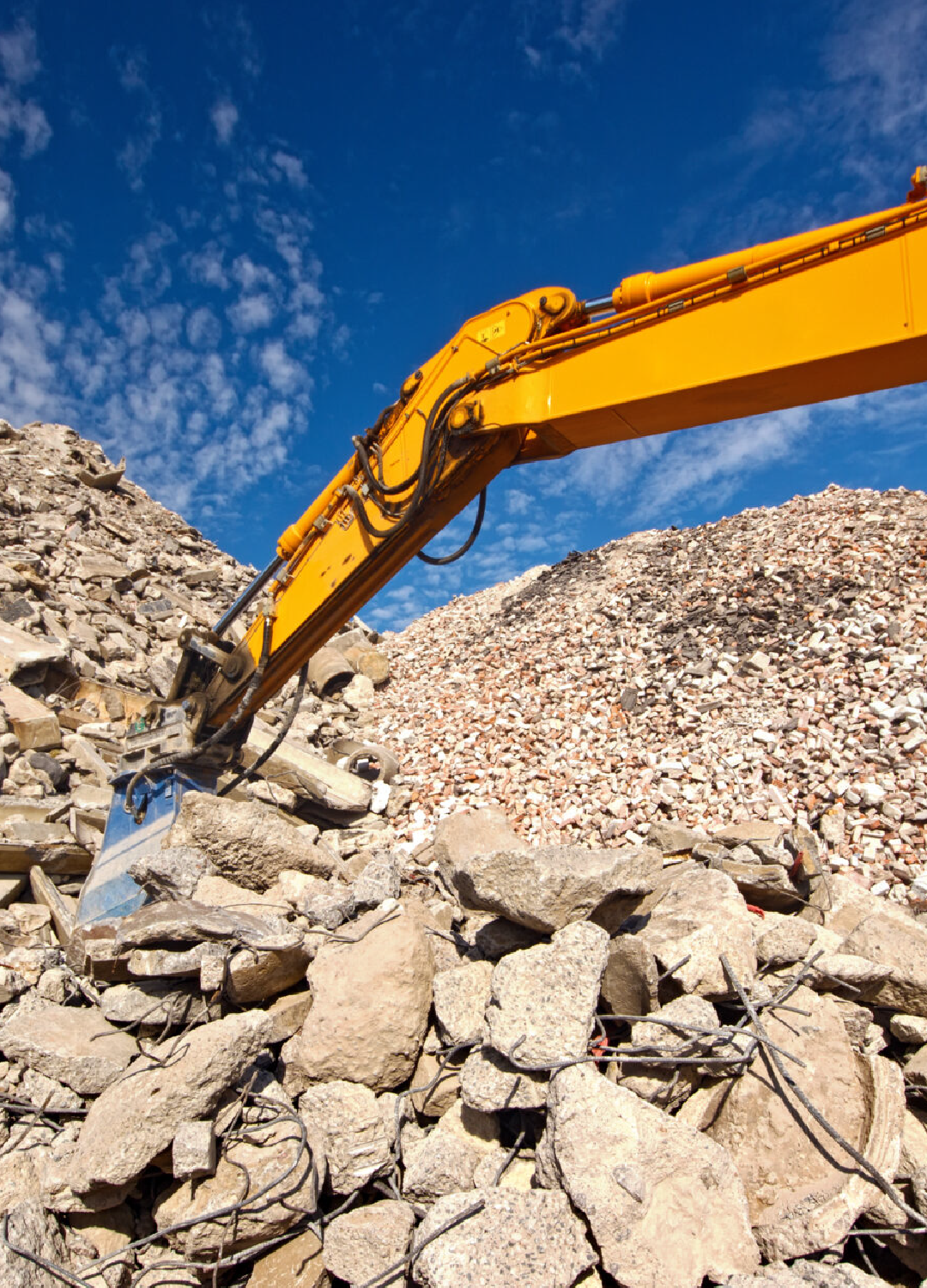 An excavator digging into a pile of rubble