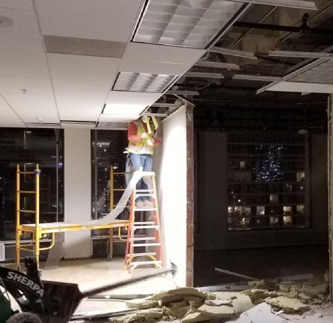 A man is standing on a ladder in a room that is being remodeled. performing commercial interior demolition in lincolnshire, il
