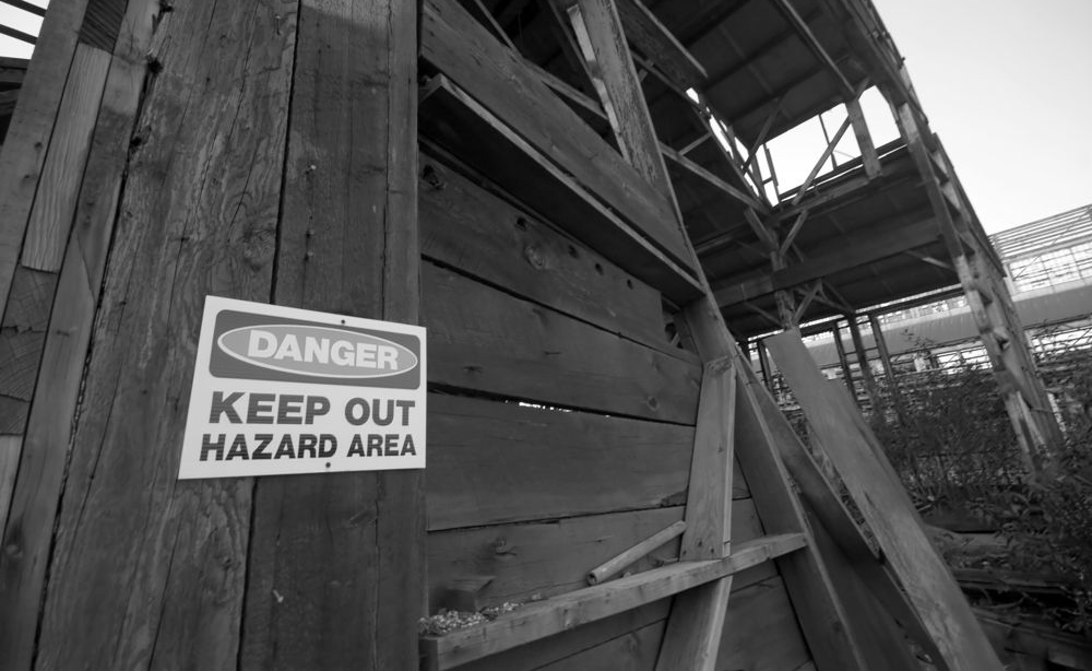 A black-and-white low-angle shot of a decaying wooden structure with a