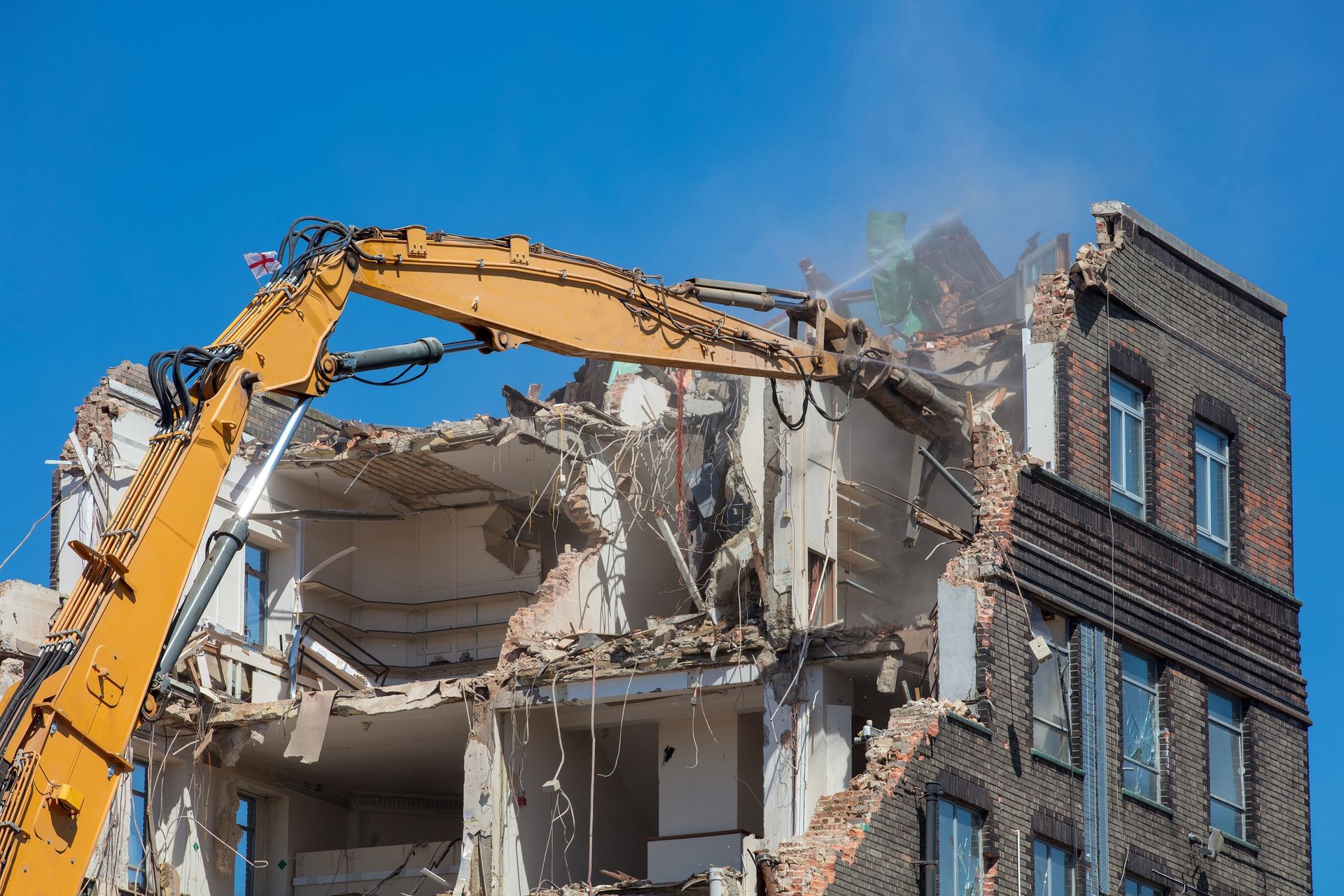 An excavator demolishing a brick building.