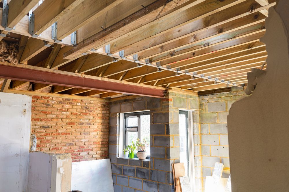 Construction site: exposed ceiling joists, steel beam, brick wall, window, concrete block walls.
