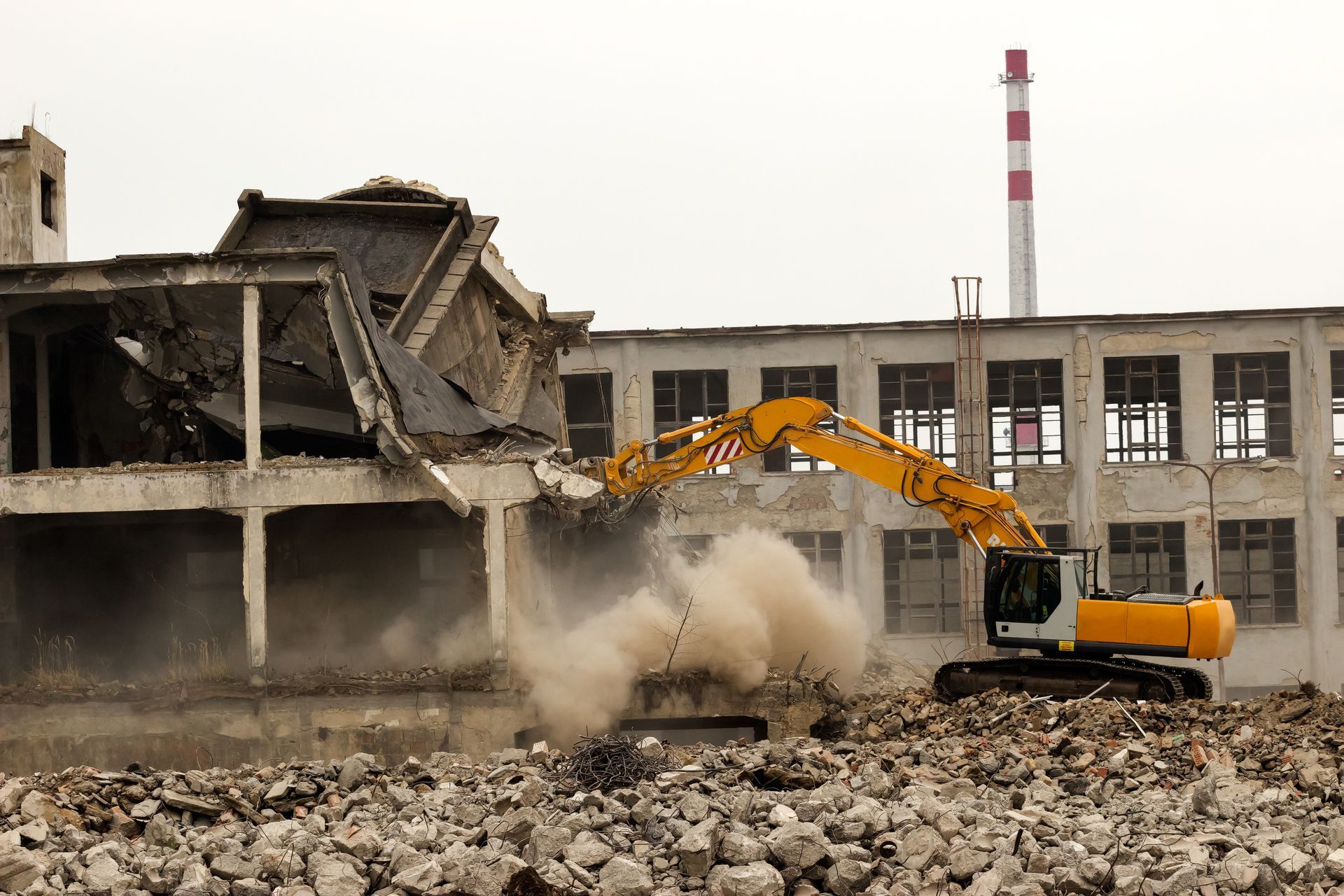 Excavator demolishing a concrete building.