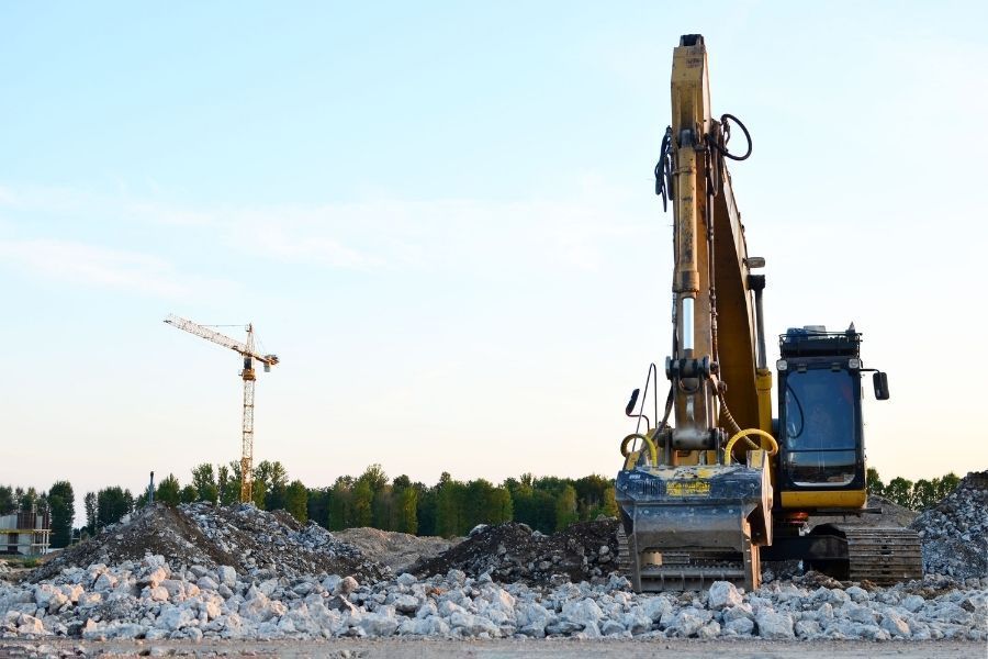 An excavator is sitting on top of a pile of rocks on a construction site.