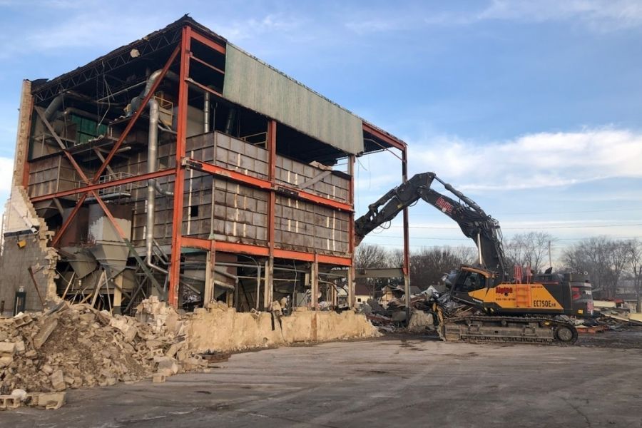 Demolition of a multi-story industrial building with an excavator.