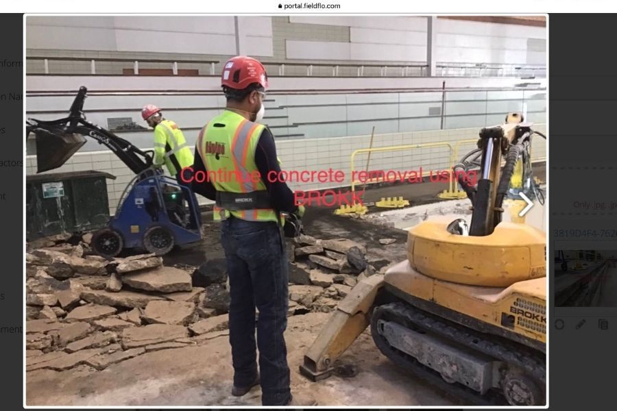 A construction worker is standing in front of a bulldozer.