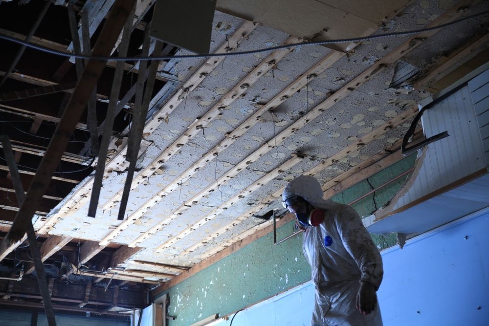 A man in a protective suit is working on commercial asbestos removal