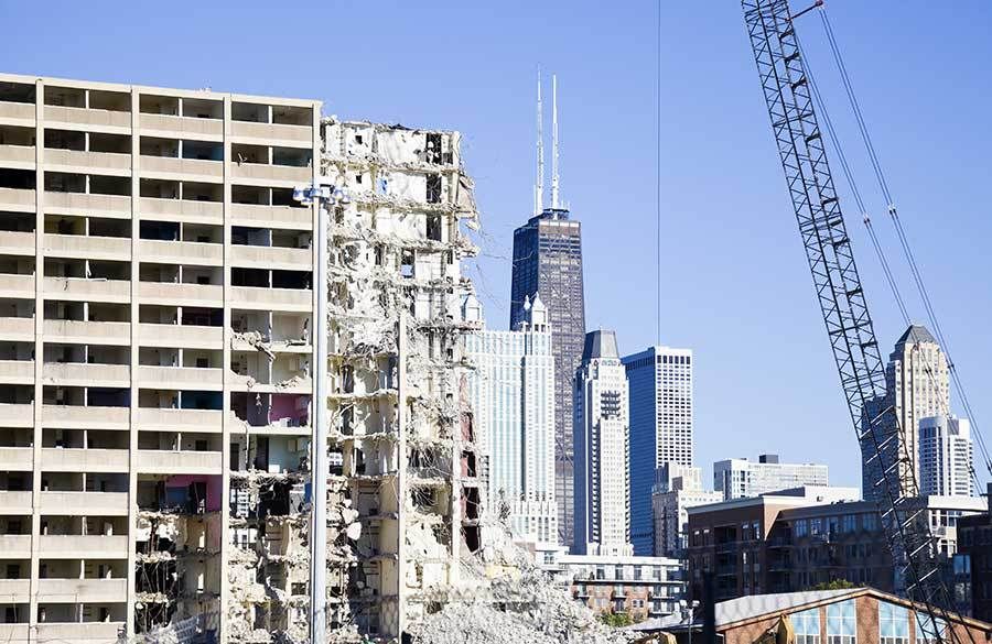 A building is being demolished in a city with a skyline in the background.