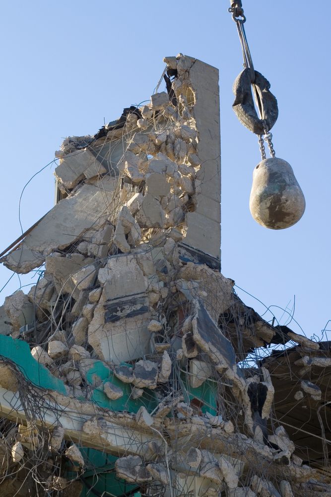 A large pile of rubble is being lifted by a crane.