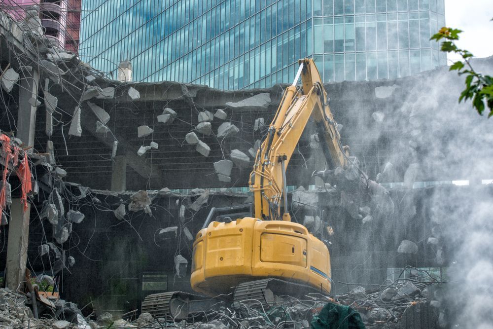 A large yellow excavator is demolishing a building.