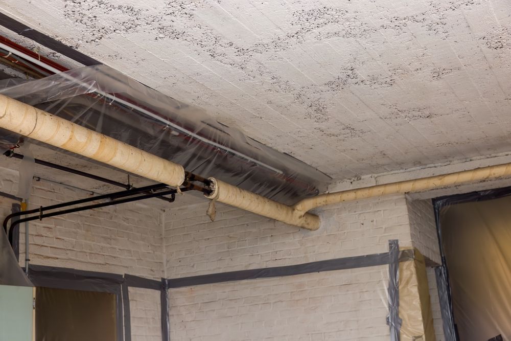 A man in a protective suit is working on the ceiling of a building.