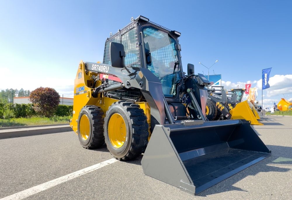A yellow and black tractor with a large bucket is parked in a parking lot.