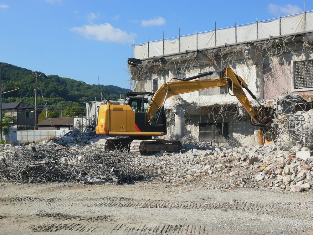A large yellow excavator is demolishing a building.