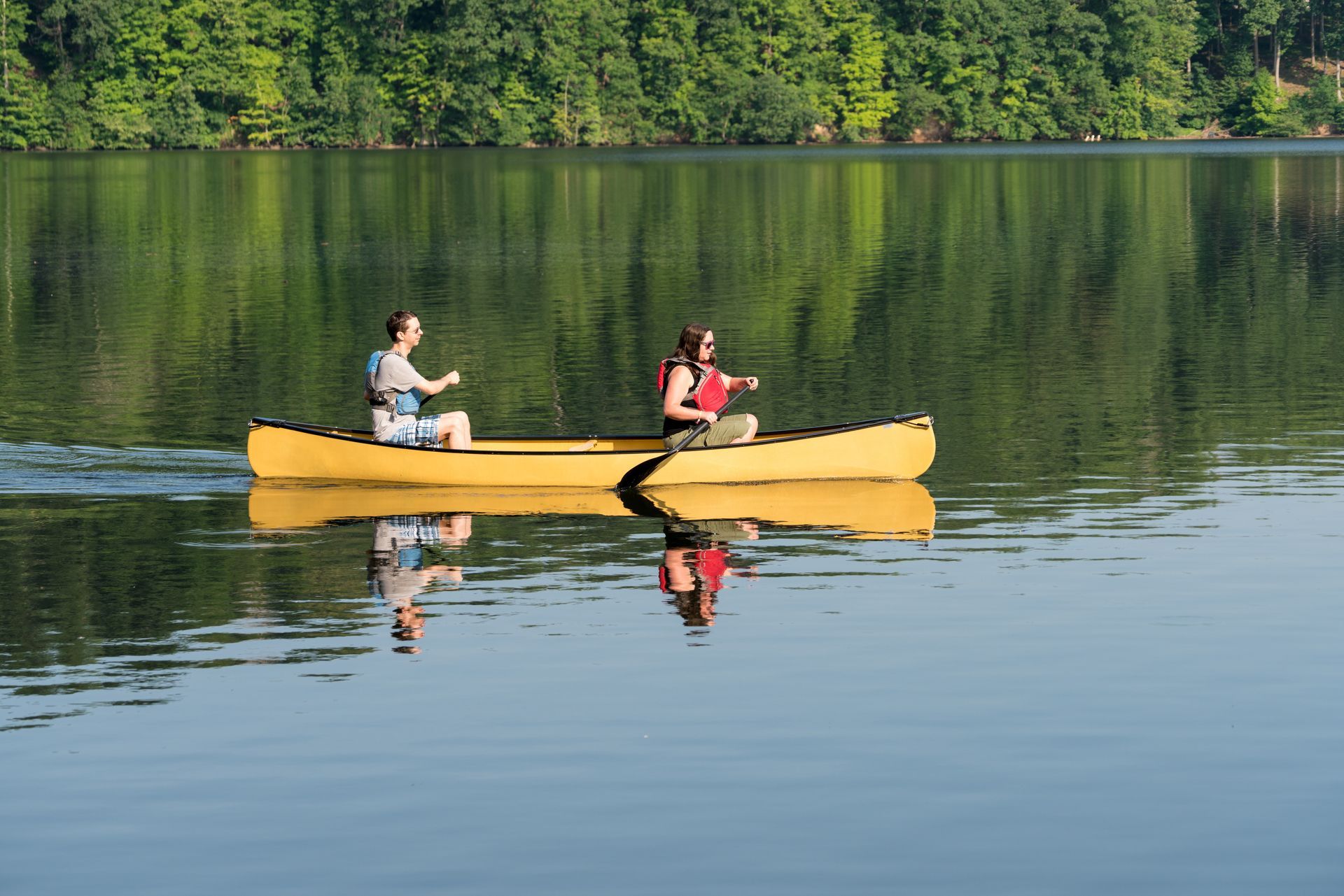 two people are rowing a canoe on a lake .