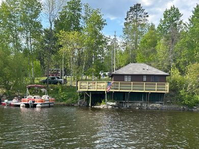 a green house is sitting on the shore of a lake surrounded by trees .