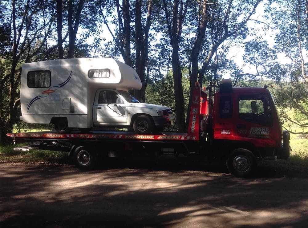 A Tow Truck Is Carrying a Camper and A Car — Alpine Towing Services in Lismore, NSW