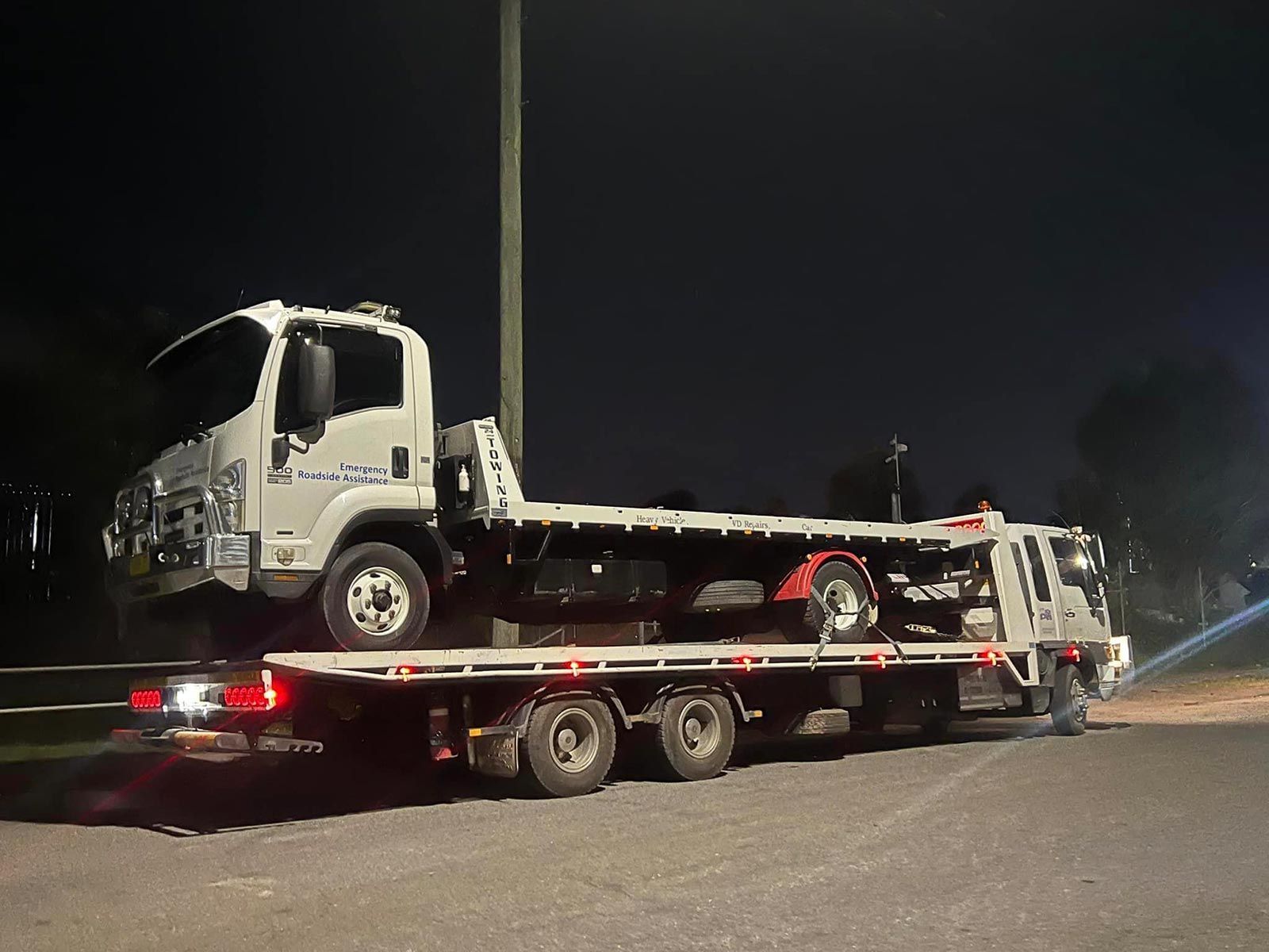 A Tow Truck Is Carrying a Car on A Flatbed Trailer — Alpine Towing Services in Lismore, NSW