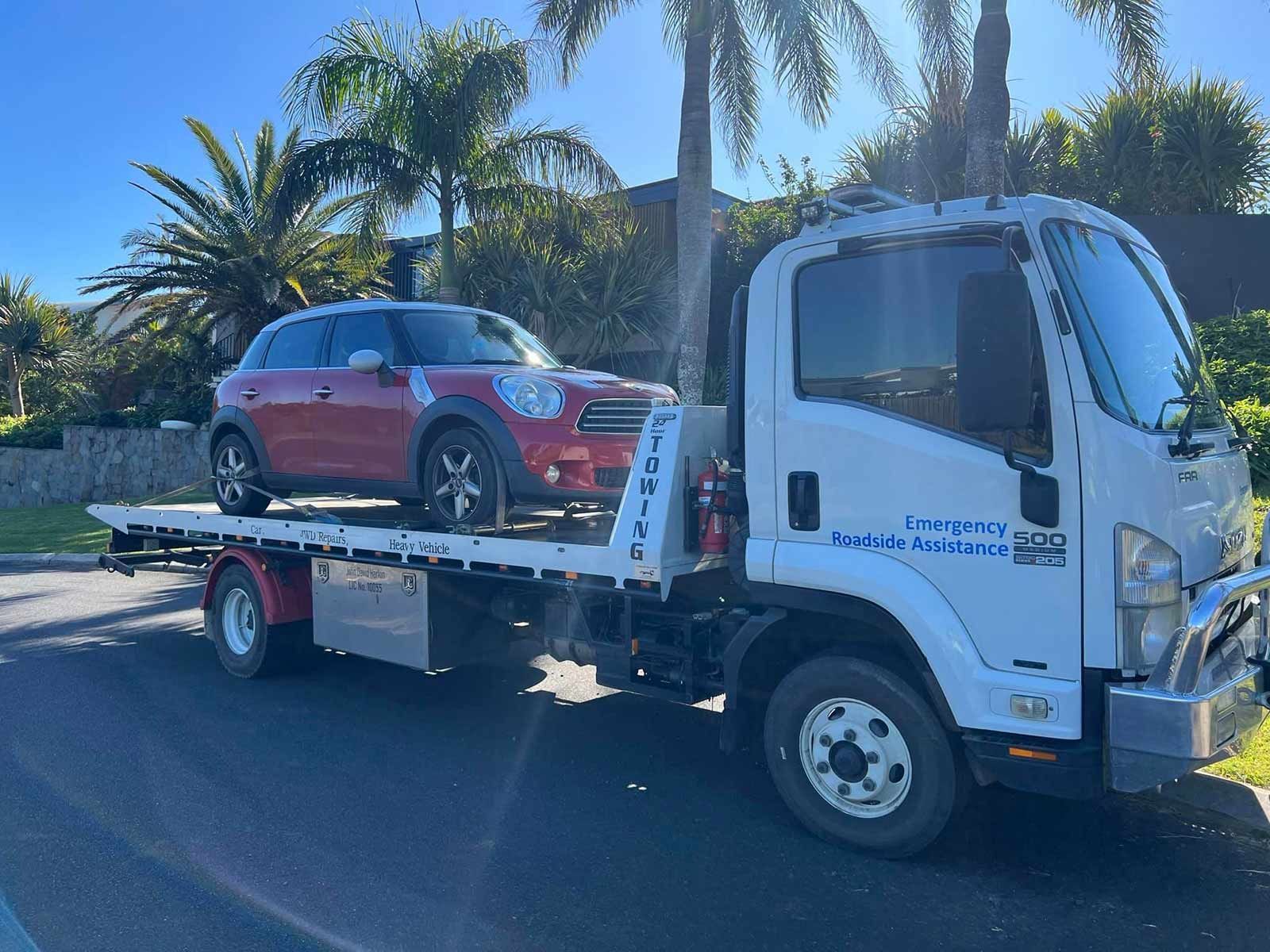 A Red Mini Cooper Is Being Towed By A Tow Truck — Alpine Towing Services in Ballina, NSW