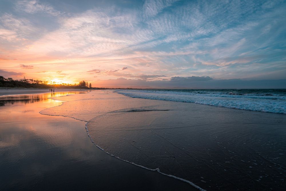 A Beach with A Sunset in The Background and Waves Crashing on The Shore — Alpine Towing Services in Byron Bay NSW