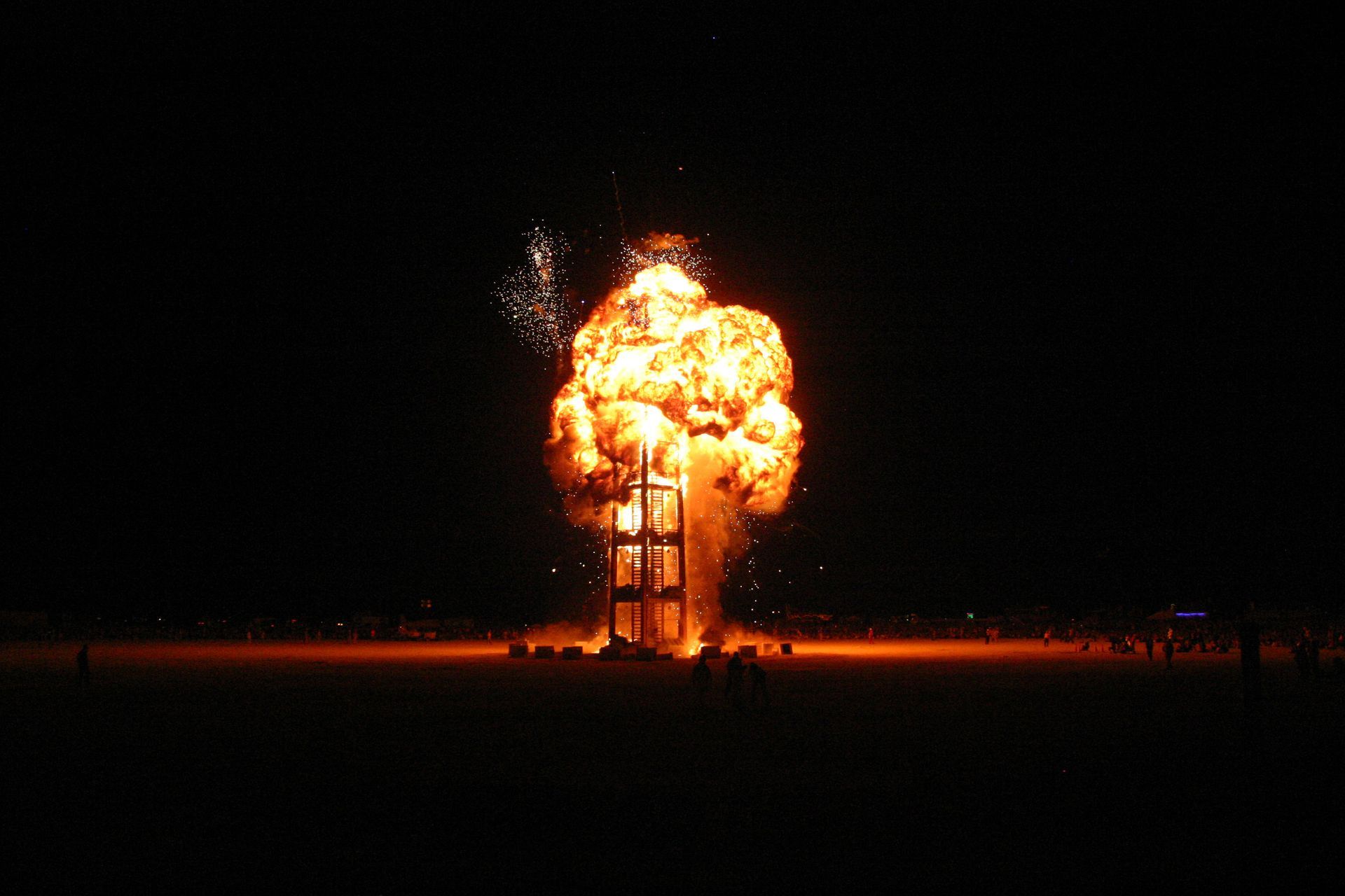 Massive fireball engulfing a structure at night, with bright orange flames against a dark sky