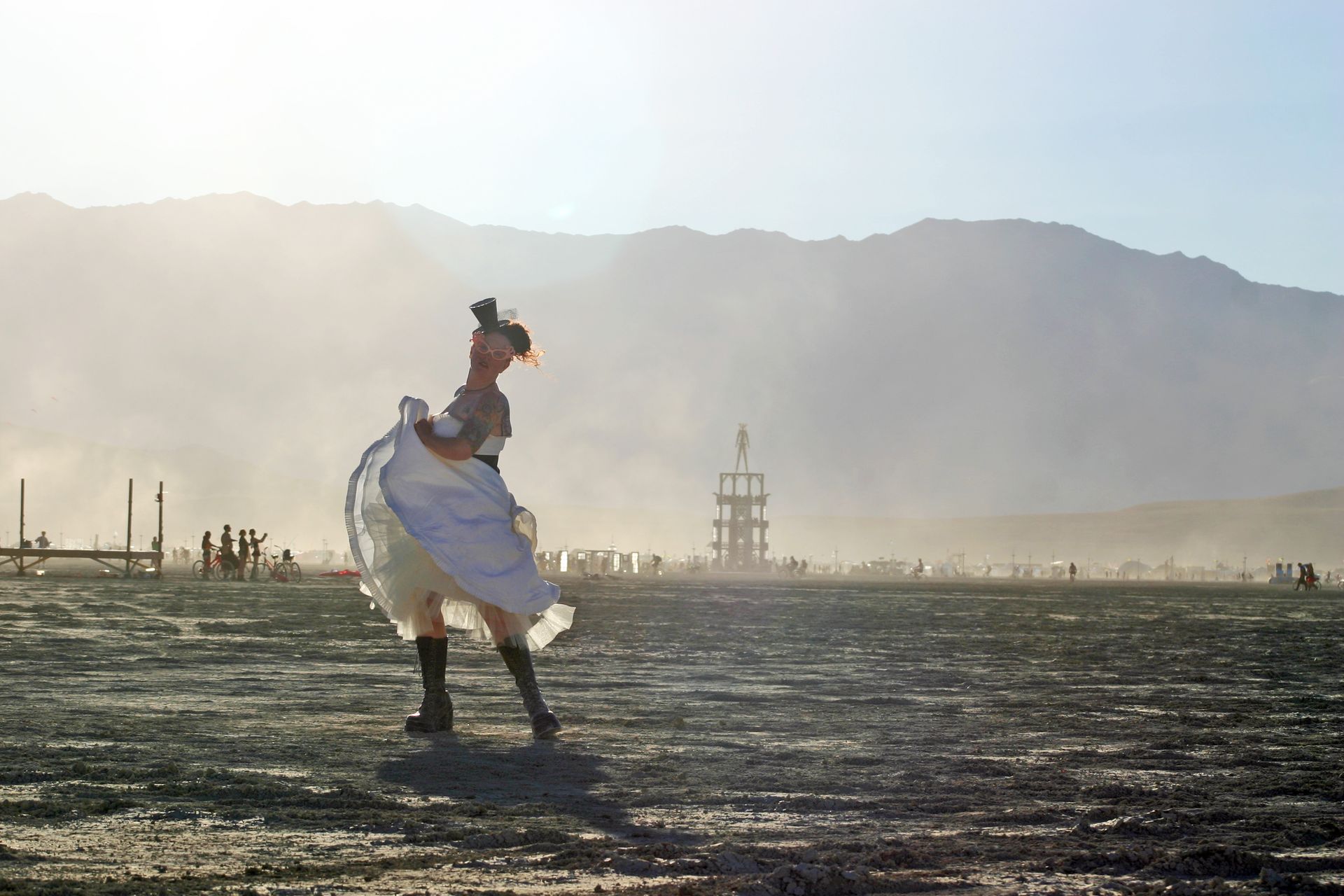 Person in a white dress dancing in a dusty desert landscape with mountains in the background
