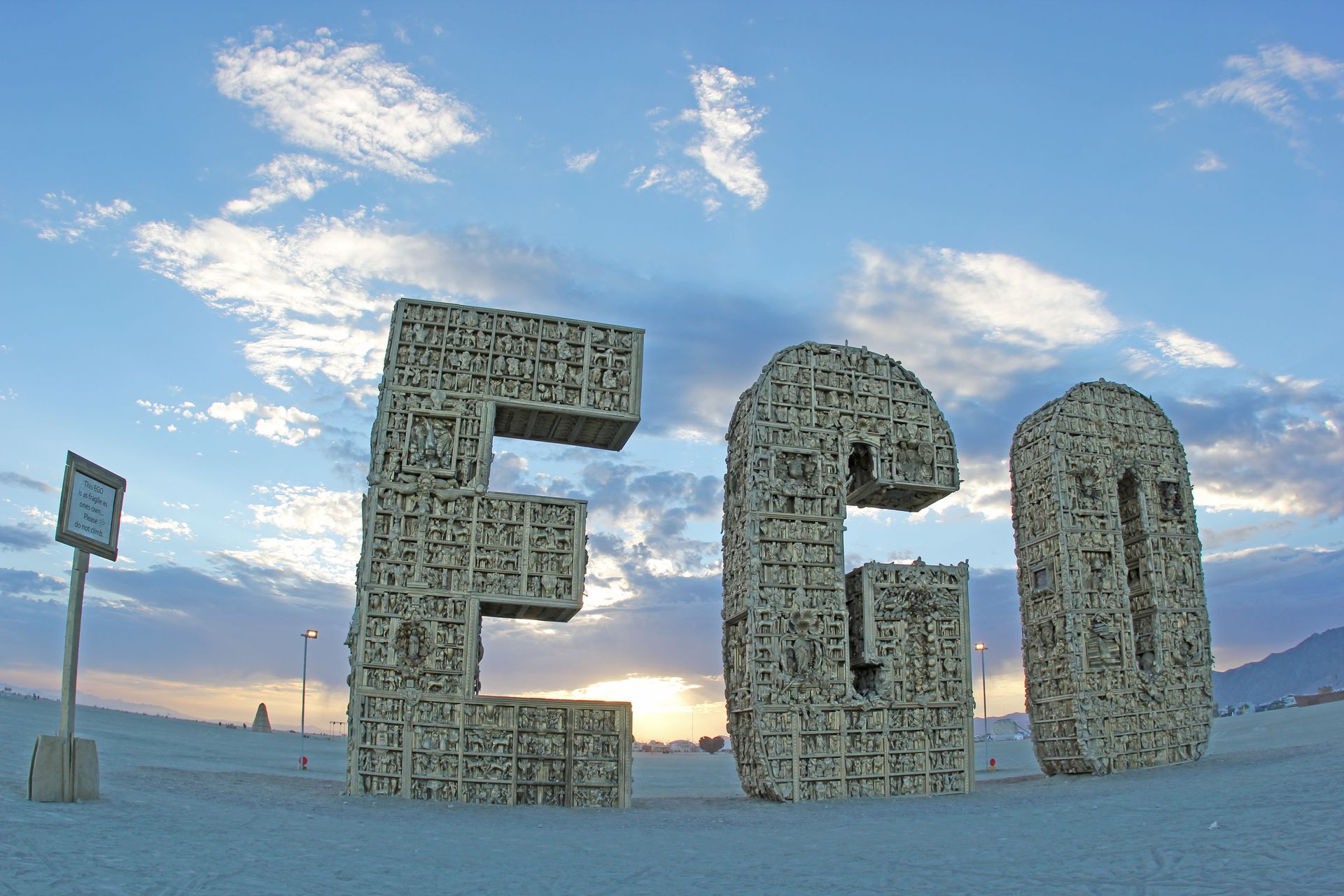 Large “EGO” letters made of small pieces stand on a snowy landscape at sunset under a blue sky.